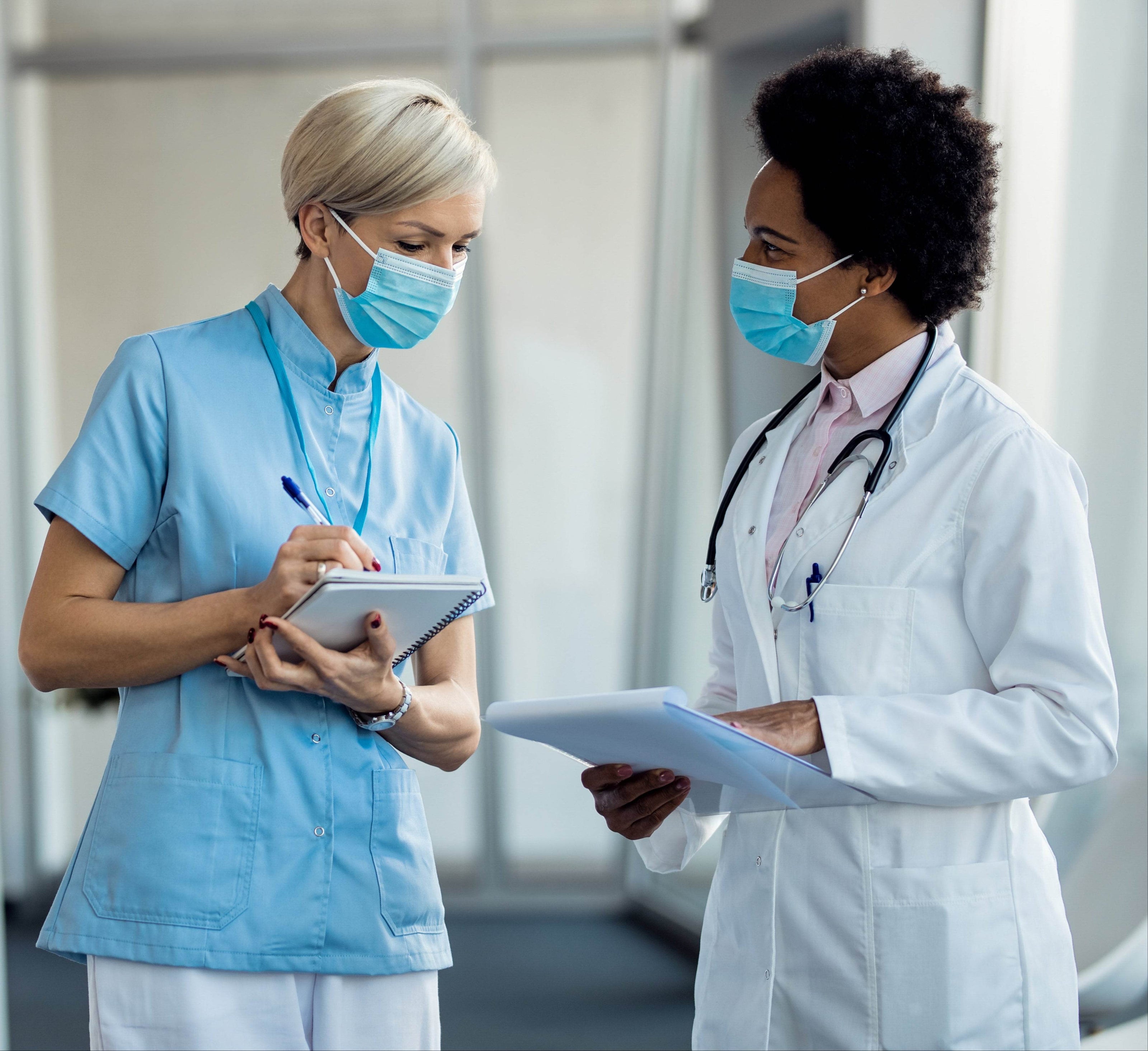 black-female-doctor-nurse-with-face-masks-communicating-hospital-hallway - ColoVantage Home